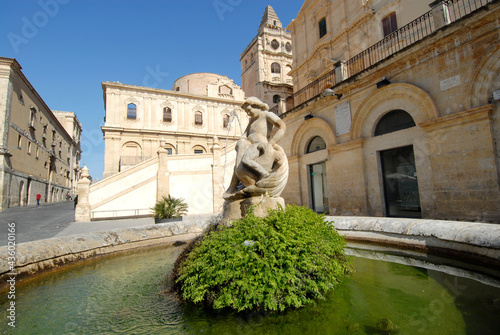 round fountain of Noto  with little angel and in the background the baroque church with large staircase of San Francesco d'Assisi all'Immacolata.

