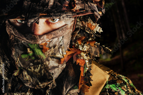 Photographie Photo of a male hunter face in panama hat and ghillie forest camouflaged suit