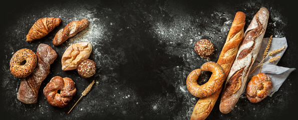 Bakery - bread rolls, baguette, bagel, sweet bun and croissant on black background