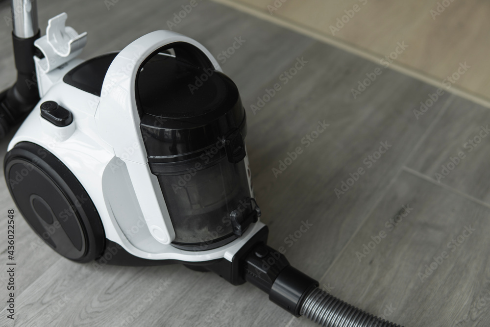 Bagless cyclone vacuum cleaner on a grey tile. Electrical apparatus that by means of suction collects dust and small particles from floors and other surfaces.