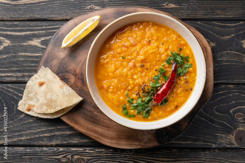 Masoor dal. Indian spicy red lentil soup, roti (chapati) are on brown wooden table. photo
