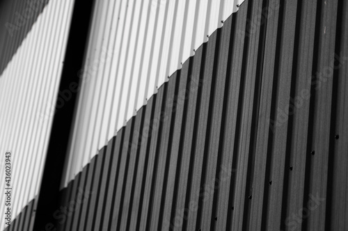 Details of black and white corrugated iron sheet used as a facade of a warehouse or factory. Texture of a seamless corrugated zinc sheet metal aluminum facade. Architecture. Metal texture.