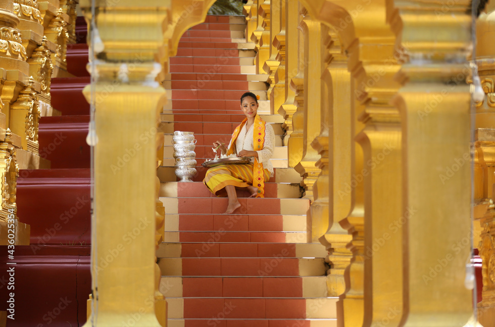 Fototapeta premium Myanmar women holding flowers at a temple. Southeast Asian young girls with burmese traditional dress visiting a Buddihist temple