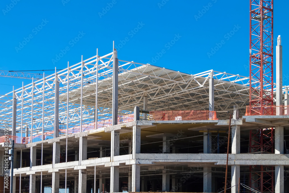 Closeup of Trade Center building during construction with steel frame shown against blue sky background. Retail shopping center under construction. Construction site where shopping mall is being built