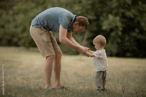 young Father with his son playing in the park in the summer. dad is holding the little boy by the arms. Family leisure concept  outdoor play  parenting. Father s day. Selective focus.