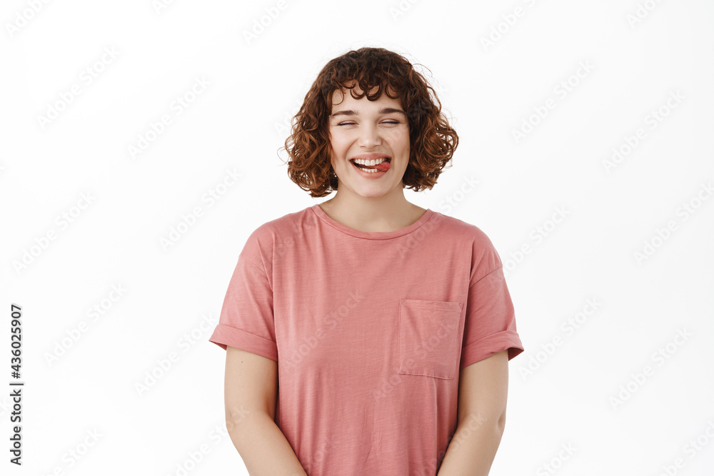 Happy beautiful young woman, laughing and smiling, showing white teeth, sticking tongue, having fun and chuckling, standing in t-shirt against white background Happy beautiful young woman, laughing and smiling, showing white teeth, sticking tongue, having fun and chuckling, standing in t-shirt against white background