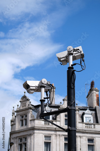 Close-up of CCTV cameras against a building and blue sky.