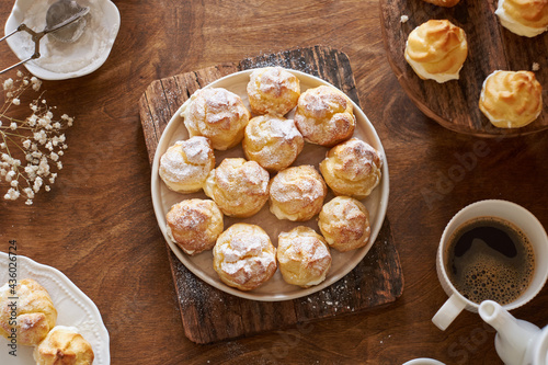 Homemade profiteroles with powdered sugar. Top view, wooden background.