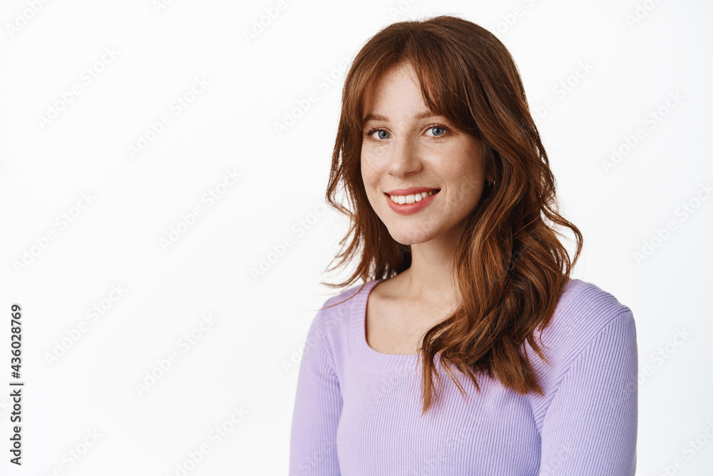 Close up of fashionable young woman with freckles and white smile, standing in purple blouse with relaxed happy face expression, looking at camera, white background Close up of fashionable young woman with freckles and white smile, standing in purple blouse with relaxed happy face expression, looking at camera, white background