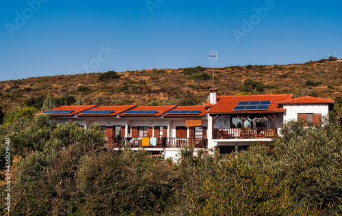Panoramic View of Countryside House with Solar Panels on Terracotta Roof Surrounded by Olive Trees on Hill in Morning Sun Light - Mountain Landscape on Sithonia Chalkidiki Greece