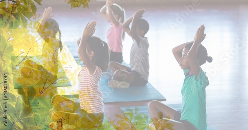 Composition of children practicing yoga on yoga mats in fitness class with tree overlay
