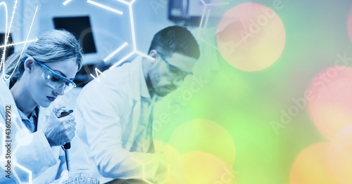 Composition of male and female lab technicians at work, with colourful bokeh copy space to right