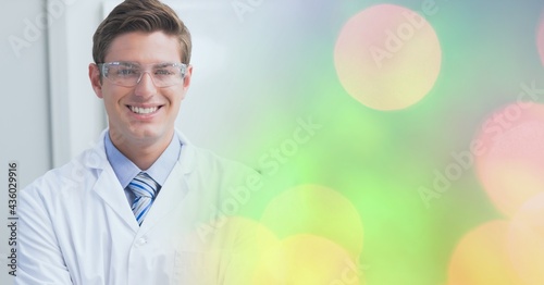 Composition of smiling male doctor, with colourful blurred copy space to right