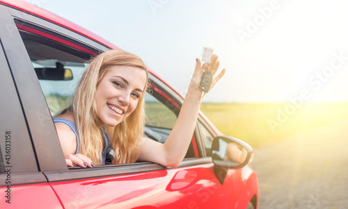 A beautiful woman in a car holds a car key in her hands. Happy young woman in the car.