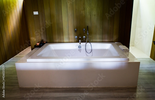 Bathroom interior decor with home spa bathtub. Modern contemporary hot tub on the dark bathroom decorated wall and floor with wood.