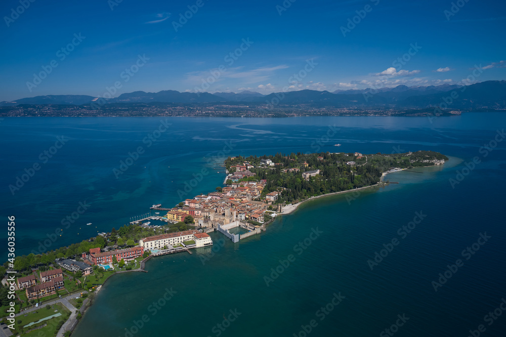 Aerial view of the island of Sirmione. Panorama of Lake Garda. Sirmione, Lake Garda, Italy. Peninsula on a mountain lake in the background of the alps. Castle on the water in Italy.