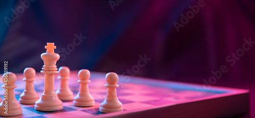 Chess pieces on a chessboard on a dark background shot in neon pink-blue colors. The figure of a chess .Close up.