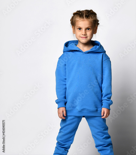 Belt portrait of a cheerful attractive girl in a blue hoodie suit smiling broadly at the camera and expressing positive emotions wjile, standing against a white background. photo