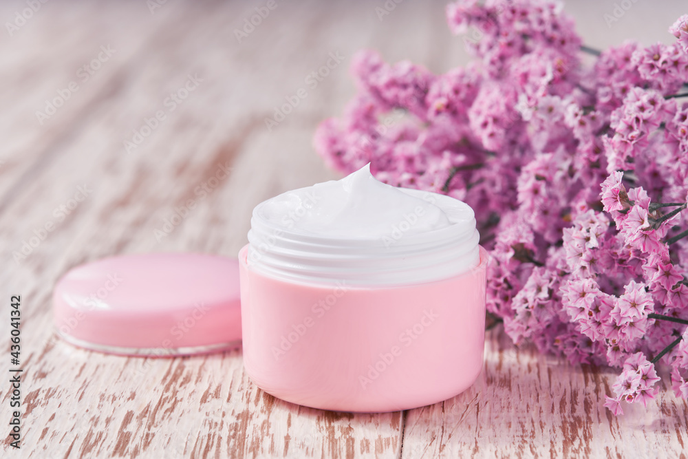 Natural face or body cream in a pink jar on a wooden table, selective focus. Natural face or body cream in a pink jar on a wooden table, selective focus.