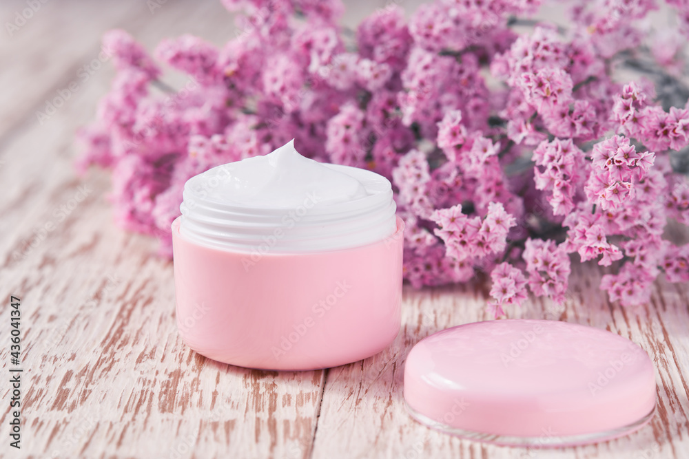 Natural face or body cream in a pink jar on a wooden table, selective focus. Natural face or body cream in a pink jar on a wooden table, selective focus.