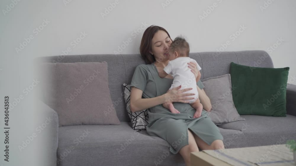 asian woman mother holding happy baby infant playing and kissing on sofa in living room at minimal style home in day time. candid authentic shot life at home. mom play with baby girl by love and care. asian woman mother holding happy baby infant playing and kissing on sofa in living room at minimal style home in day time. candid authentic shot life at home. mom play with baby girl by love and care.