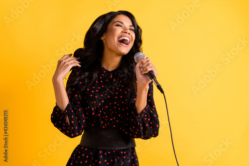 Photo of pretty cheerful dark skin girl closed eyes open mouth singing loud isolated on yellow color background photo