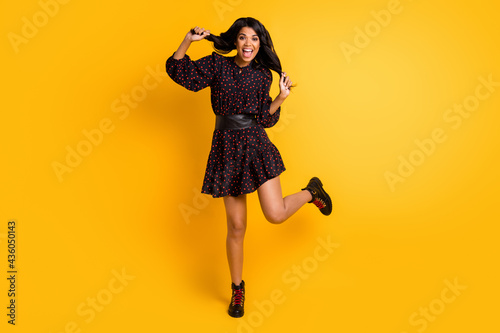 Full length photo of funky funny dark skin lady wear dotted dress dancing holding arms hair isolated yellow color background