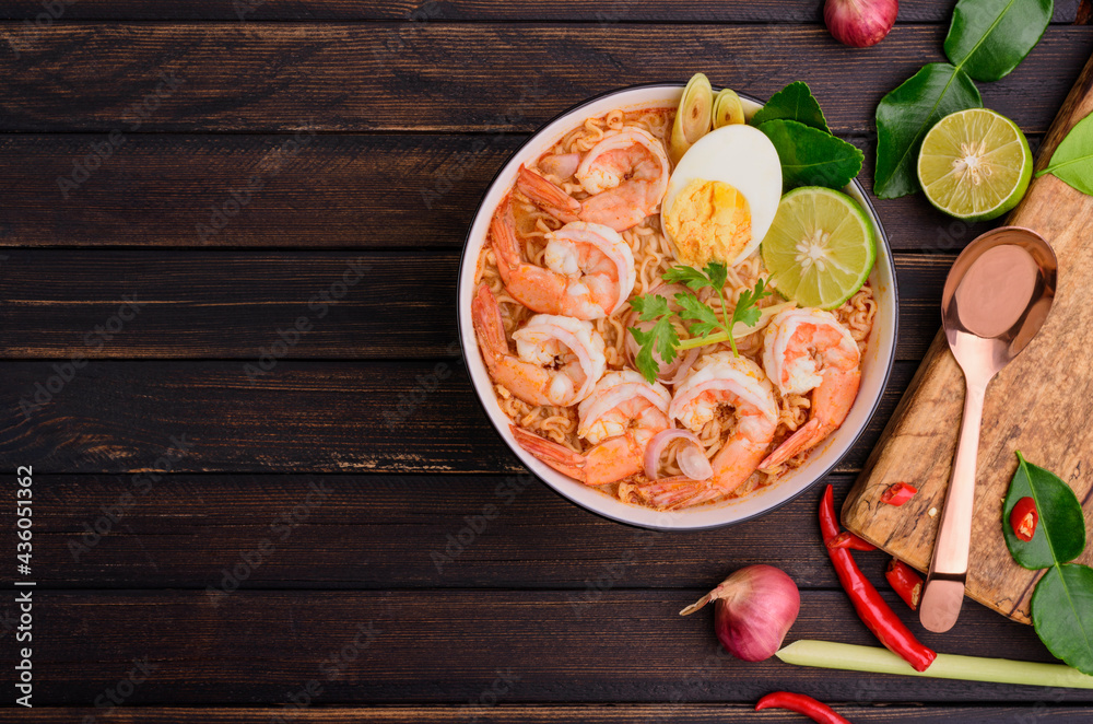 Shrimp Tom Yum Noodle Ramen Contains galangal, lemongrass, kaffir lime leaves, lime, chili - a popular dish. It has a very spicy Asian style. Placed on a black wooden table with top view copy area.