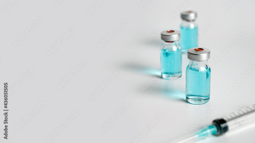 Close up of Covid-19 vaccine vials and syringe on white background. Hand takes one bottle of vaccine. Medical vaccination concept banner. Close up of Covid-19 vaccine vials and syringe on white background. Hand takes one bottle of vaccine. Medical vaccination concept banner.