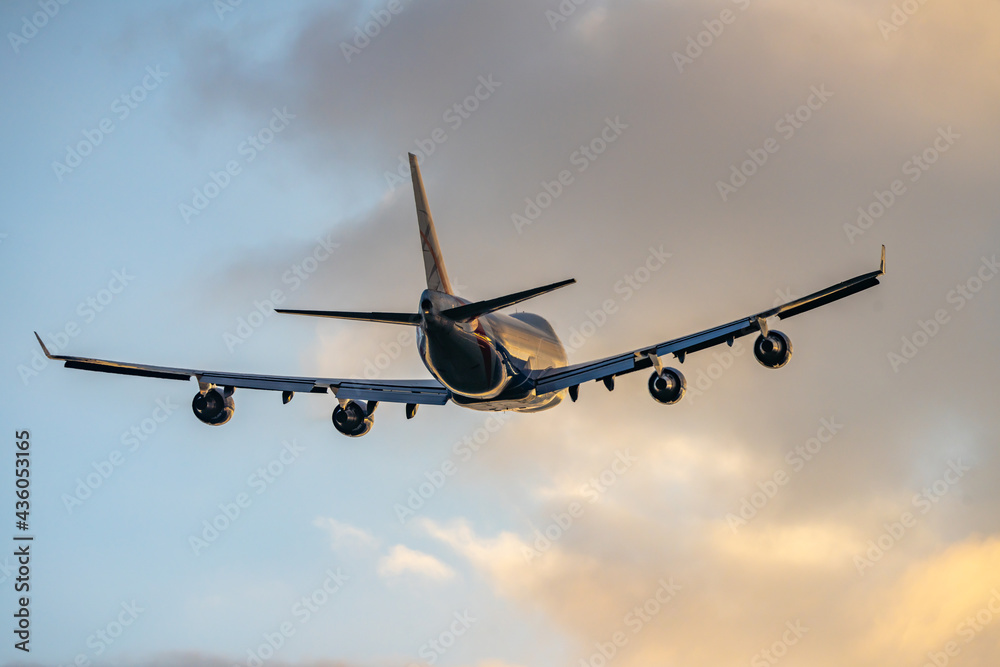 Jumbo jet four big engines flying off taking tourists abroad from airport on holiday into golden sunset summer sky. Creamy gold clouds and silhouette of aeroplane taking off and flying away. Jumbo jet four big engines flying off taking tourists abroad from airport on holiday into golden sunset summer sky. Creamy gold clouds and silhouette of aeroplane taking off and flying away.