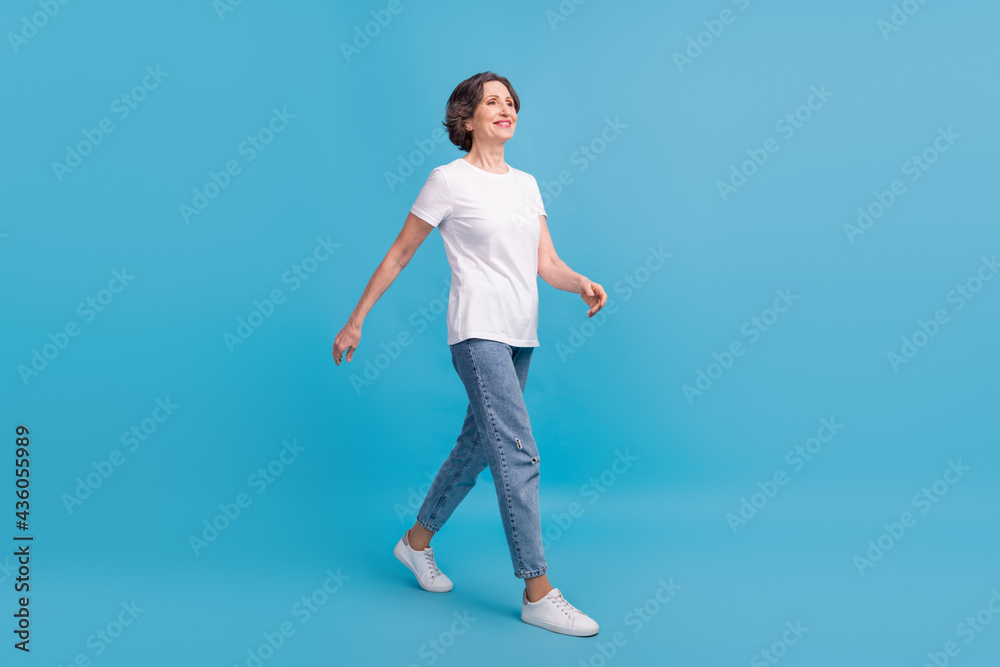 Full length body size view of attractive cheerful woman walking isolated over vibrant blue color background