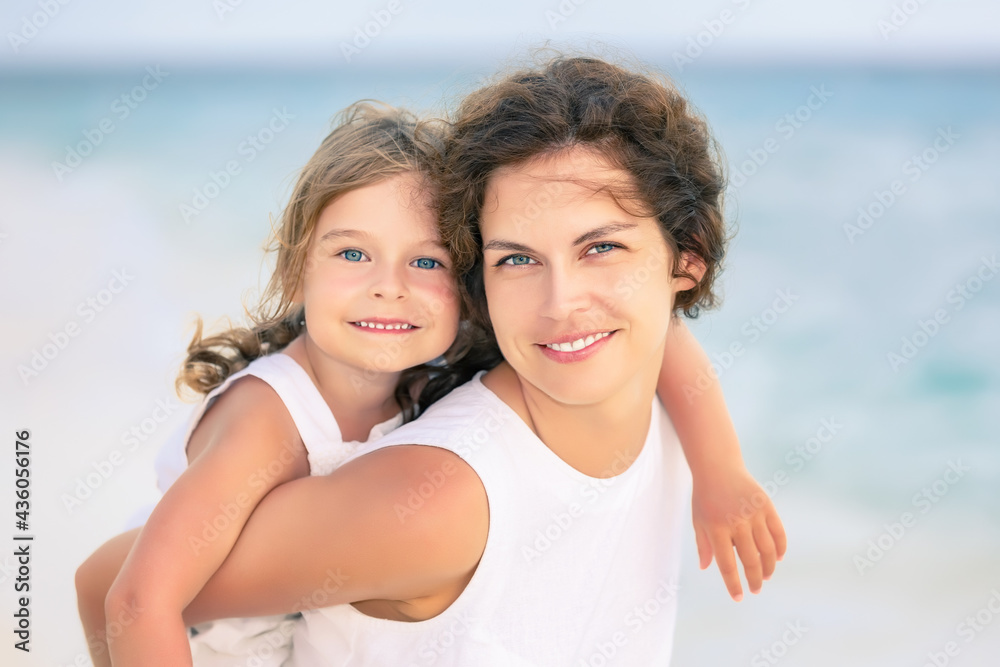 Portrait of happy mother and little daughter on ocean beach on Maldives at summer vacation. Family on the beach concept.