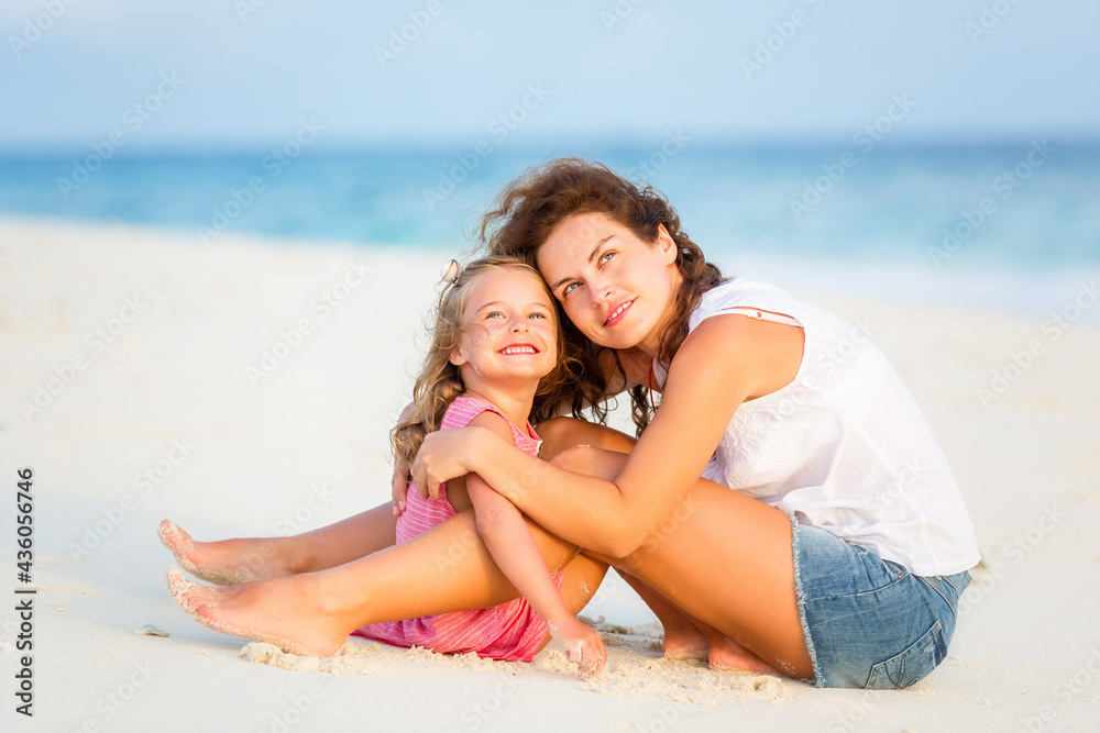 Mother with little daughter resting on ocean beach, Maldives. Family on the beach concept.