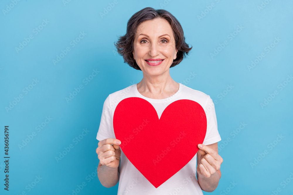 Portrait of attractive cheerful woman holding in hands big red heart amour care isolated over bright blue color background Portrait of attractive cheerful woman holding in hands big red heart amour care isolated over bright blue color background