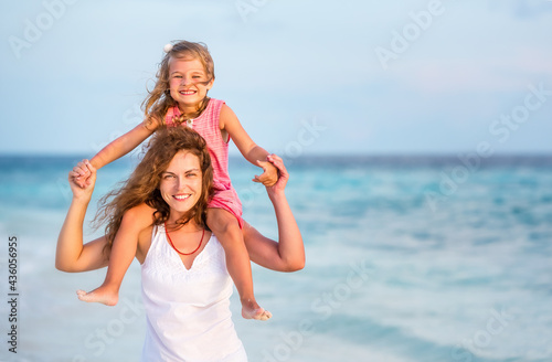 Happy mother and little daughter having fun on beach on Maldives at summer vacation. Family on the beach concept. © sborisov