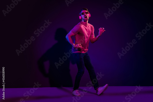 Full length body size view of nice cheerful funny guy listening sound pretending playing guitar isolated over dark neon violet color background