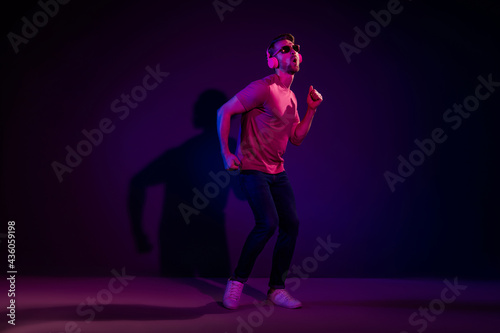 Full length body size view of nice cheerful guy listening bass hit having fun dancing isolated over dark neon violet color background