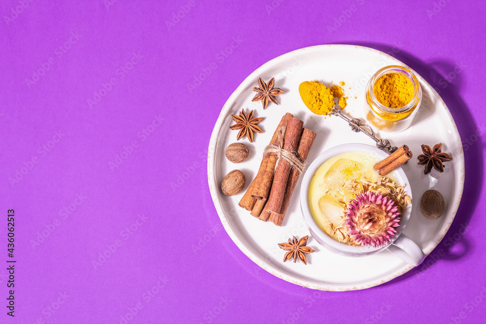 Golden turmeric milk with ice on bright yellow background