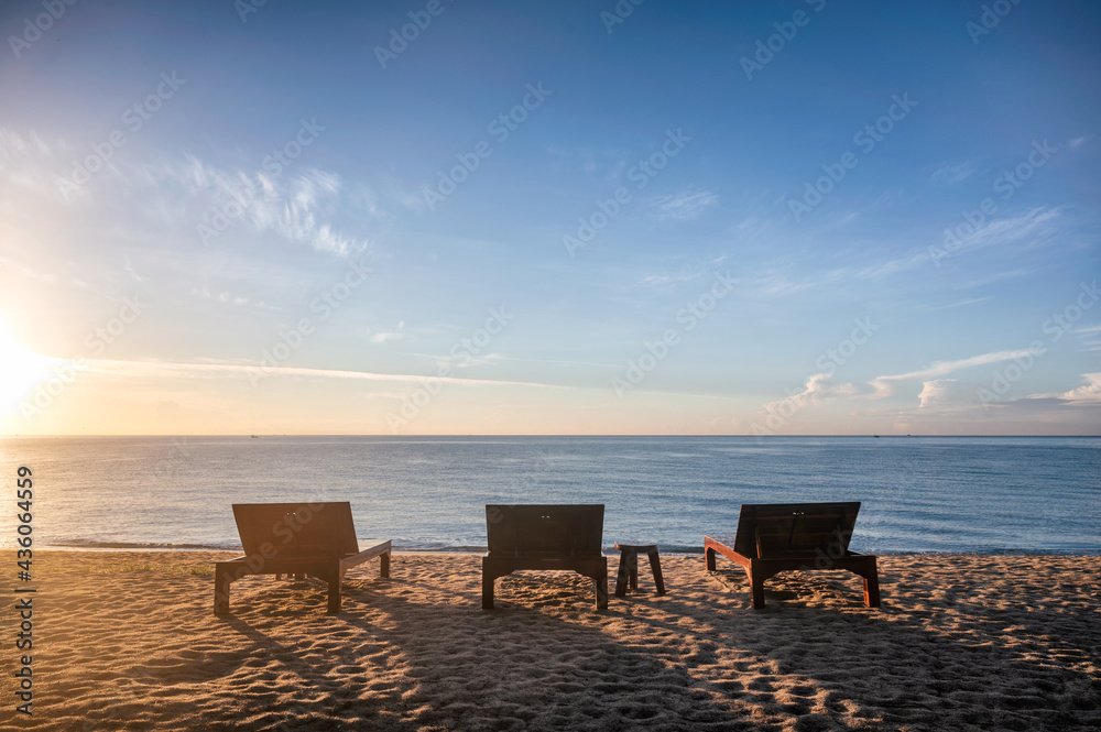 Three wooden sunbed lounge with sunshine on the beach in tropical sea