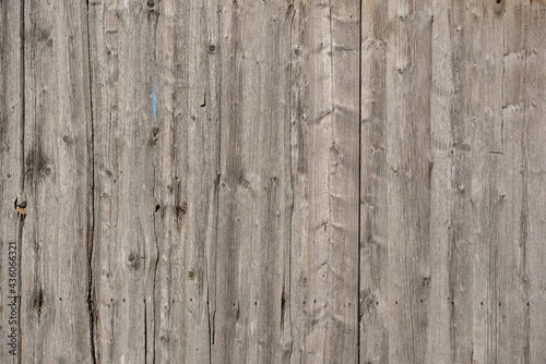 The background and texture of a wall made of old faded wood partially showing the blue sky, outdoors