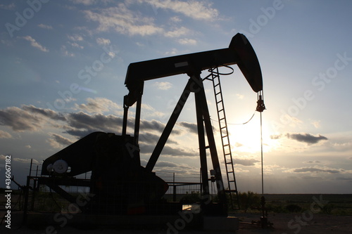 Pump jack producing oil in the West Texas Permian Basin with sunset in background