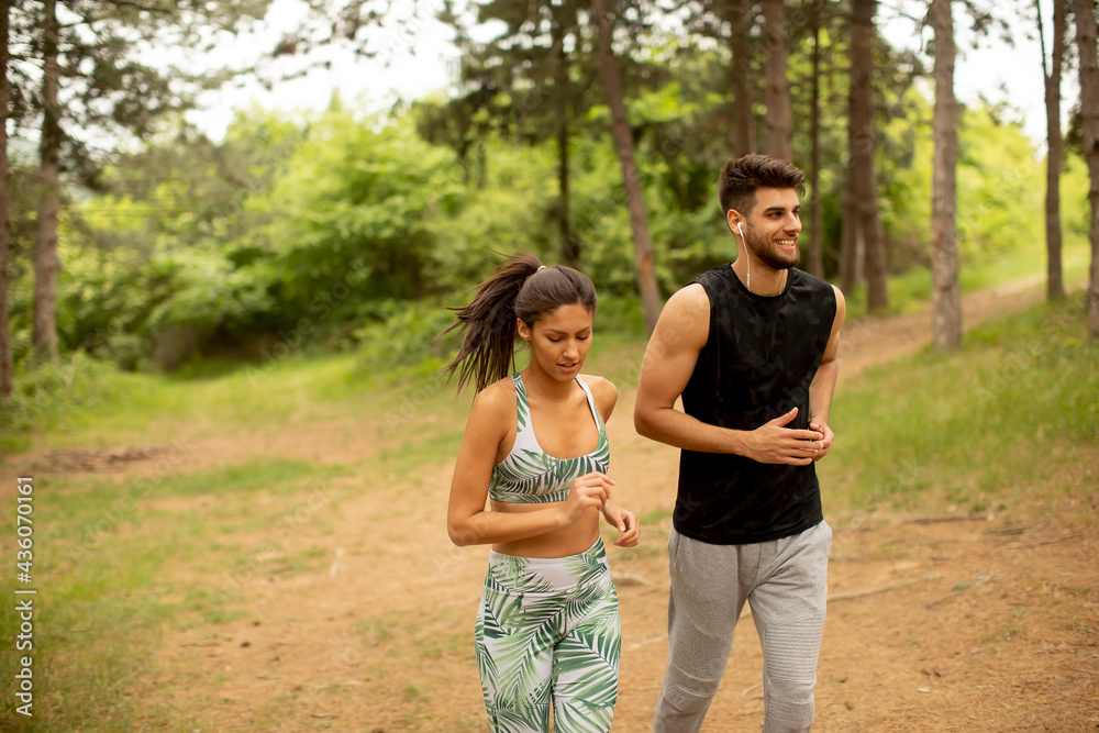 Young fitness couple running at the forest trail Young fitness couple running at the forest trail