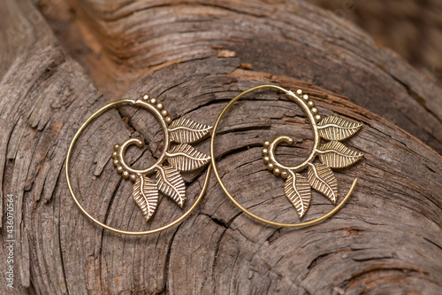 Ornamental brass metal earrings on natural background