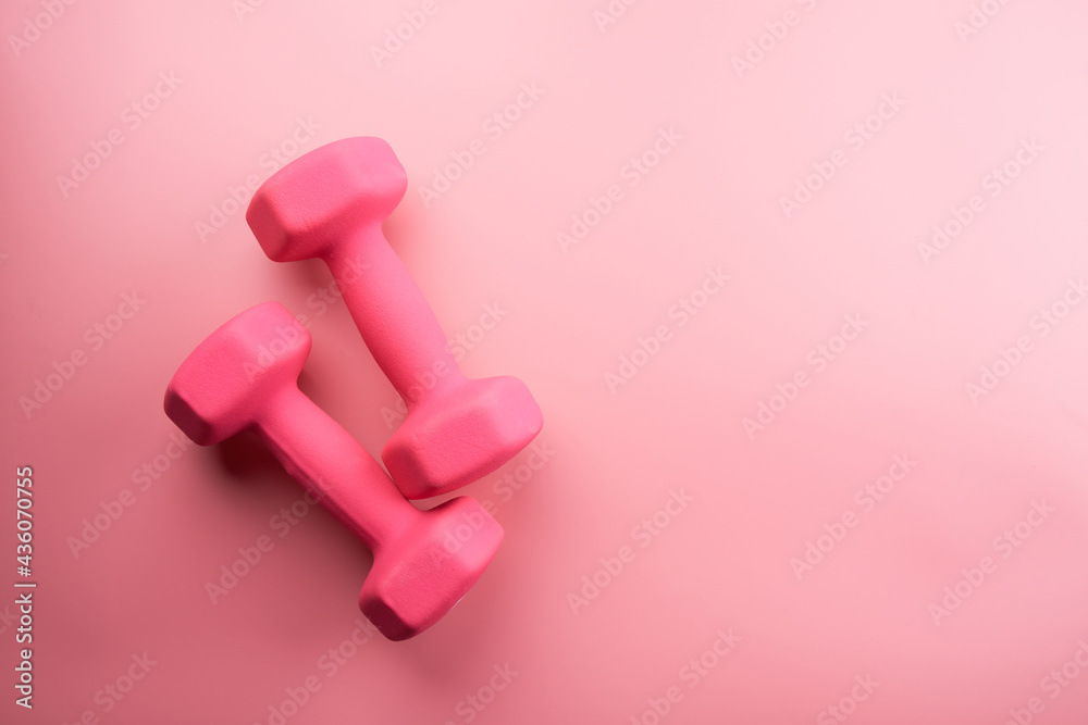 Two pink female dumbbells isolated on pink background close-up with copy space. Fitness concept, weight loss and sport activity, top view, flat lay Two pink female dumbbells isolated on pink background close-up with copy space. Fitness concept, weight loss and sport activity, top view, flat lay