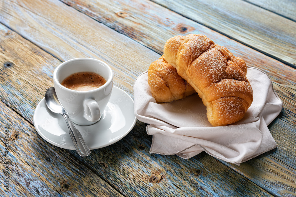 View from above. Cup of hot Italian espresso coffee and croissants on a light blue rustic wooden background. Food and drink. Lifestyle. View from above. Cup of hot Italian espresso coffee and croissants on a light blue rustic wooden background. Food and drink. Lifestyle.