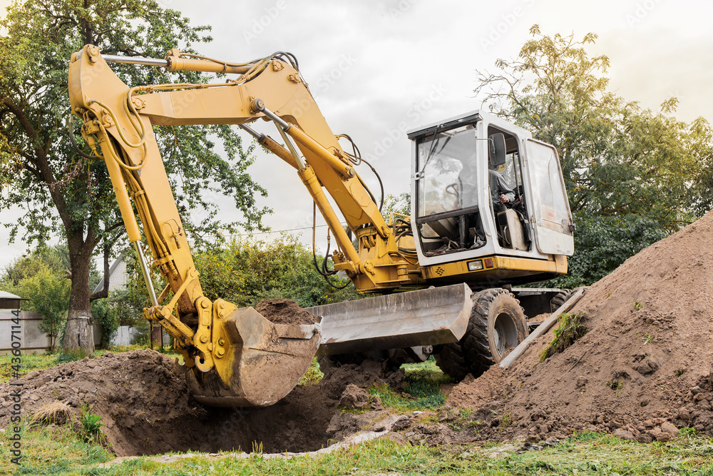 A bucket of excavator pours the ground into a heap against the background of a rural industrial zone. Bulldozer work on the construction site A bucket of excavator pours the ground into a heap against the background of a rural industrial zone. Bulldozer work on the construction site