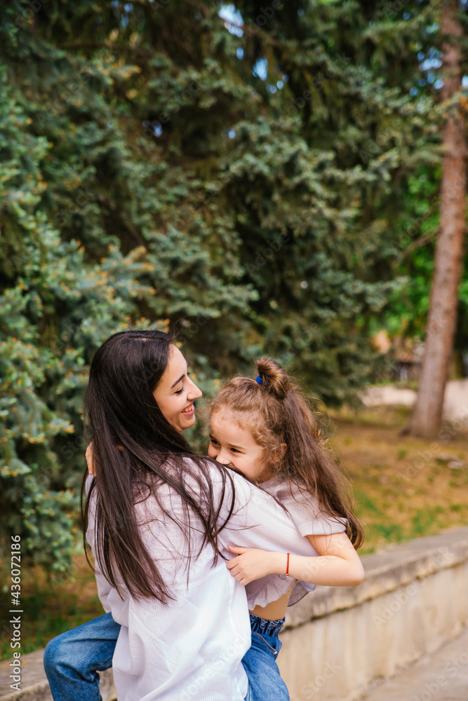 A young woman and her daughter are circling in their arms. Mom and daughter laugh and have fun.
