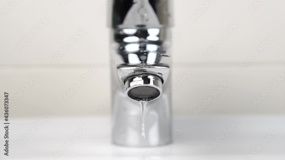 Dripping stainless faucet with water drops close-up. Fluid leaking from a broken valve with a strainer. Falling droplet in slow motion. The concept of saving and wasteful use of natural resources Dripping stainless faucet with water drops close-up. Fluid leaking from a broken valve with a strainer. Falling droplet in slow motion. The concept of saving and wasteful use of natural resources