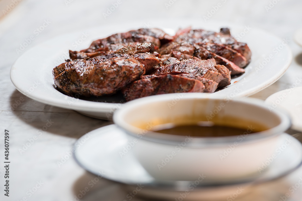 Grilled medium steak slices with a side of soy sauce.