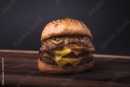 Closeup of a fresh double cheeseburger with and bacoon a wooden board photo